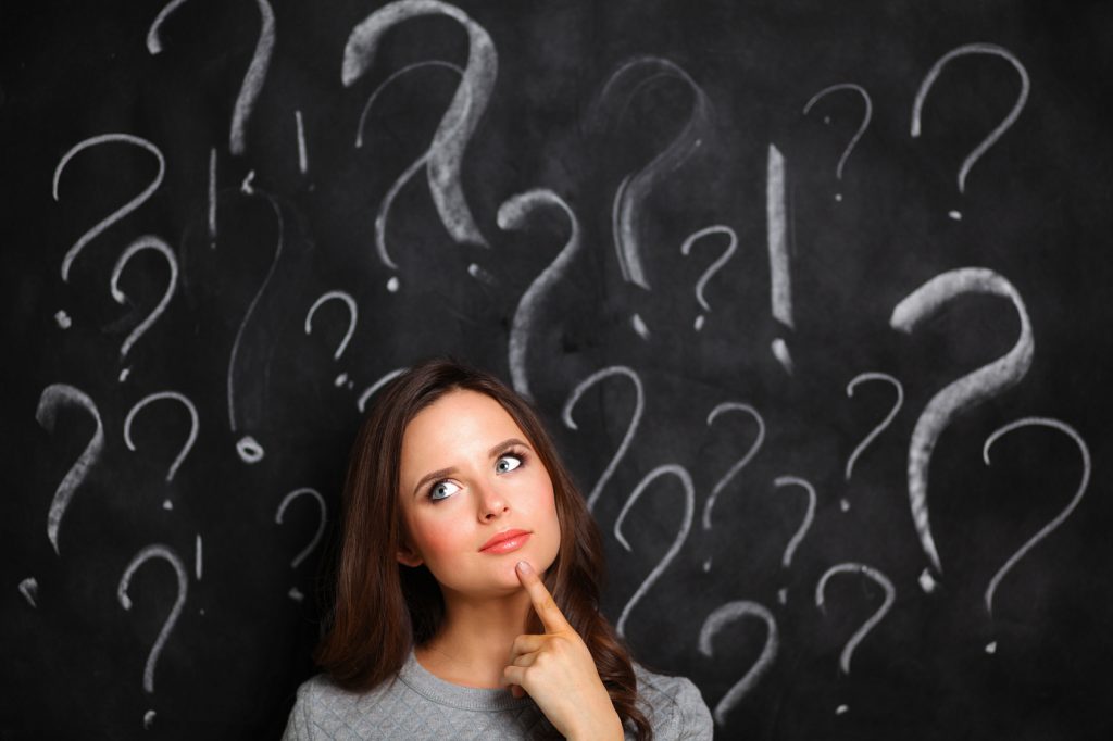 Young girl with question mark on a gray background .