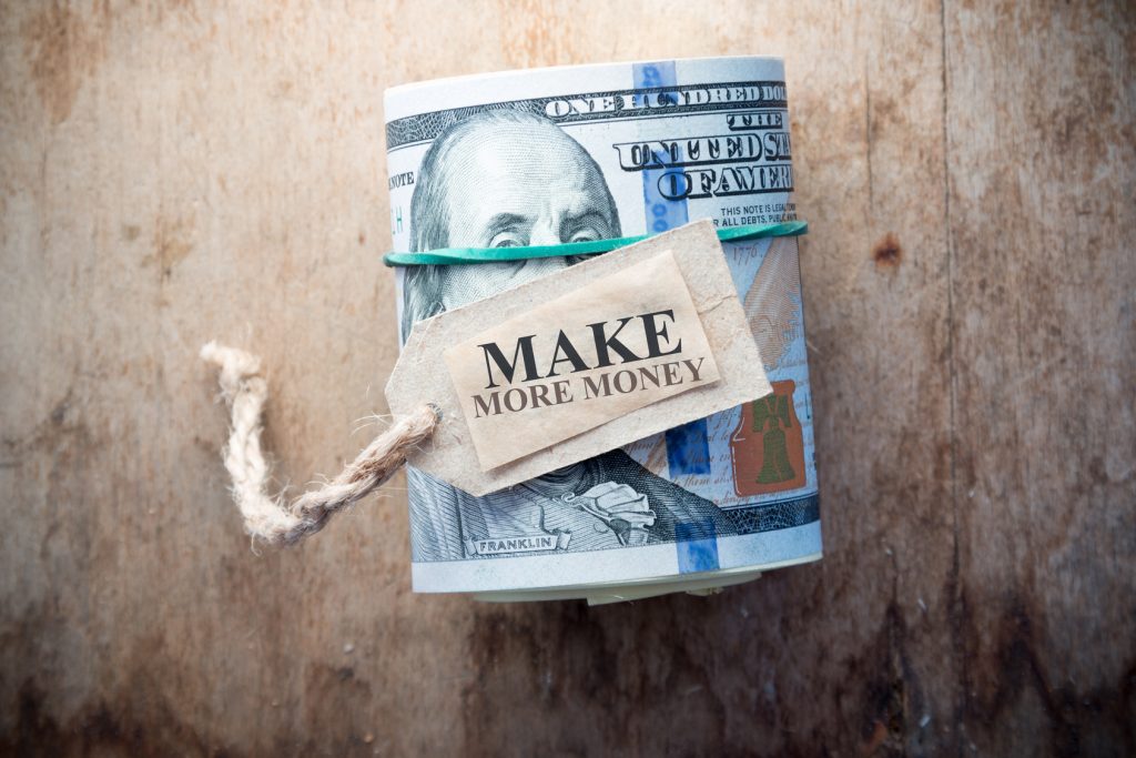Make More Money, inscription, on the background wooden table and one hundred dollar bills.